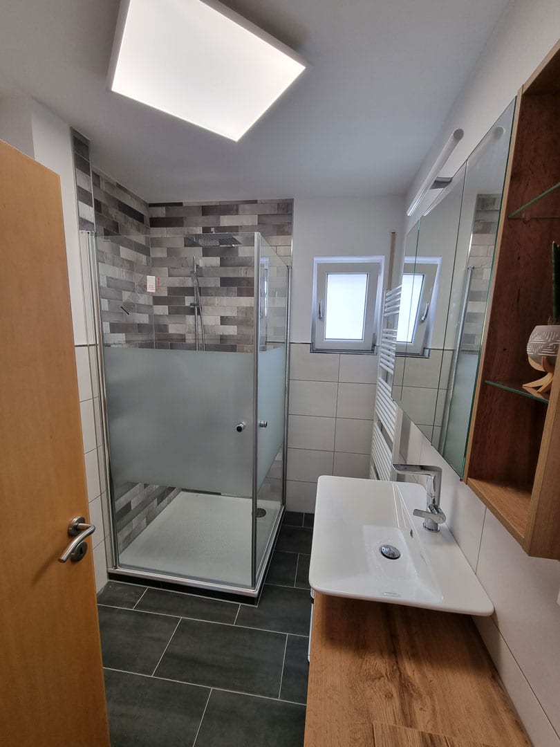 Ergebnis der Sanierung eines Badezimmers mit neuer Verfliesung von Wand und Boden sowie erneuerten Sanitärobjekten