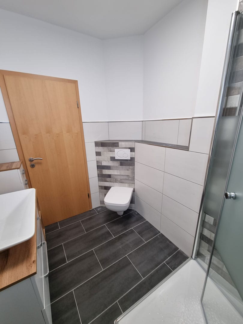 Sanierung eines Badezimmers mit neuer Verfliesung von Wand und Boden sowie Erneuerung der Sanitärobjekte