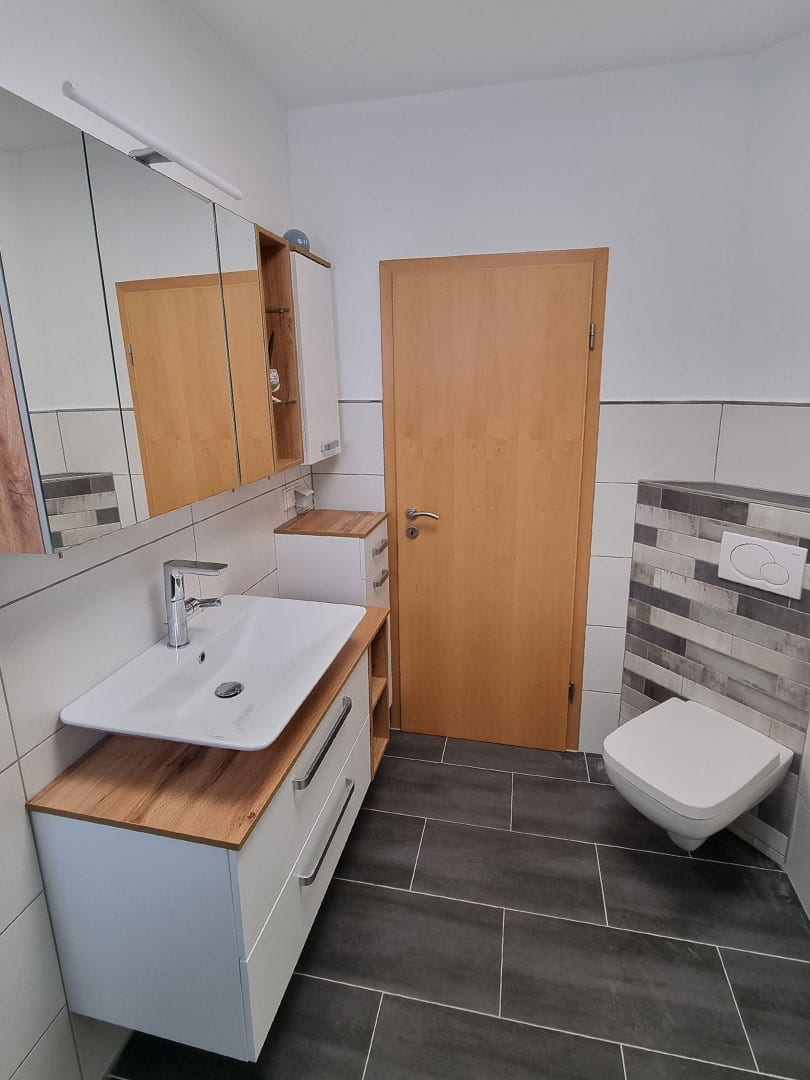 Ergebnis Sanierung eines Bads mit neuer Verfliesung von Wand und Boden sowie erneuerten Sanitärobjekten