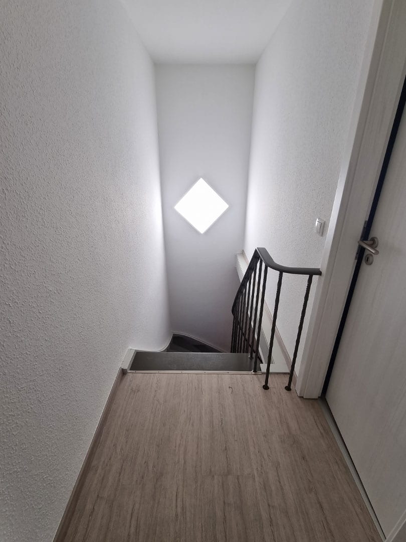 Sanierung eines Hauses mit neuer Tapete, neuem Bodenbelag und lackierter Treppenanlage