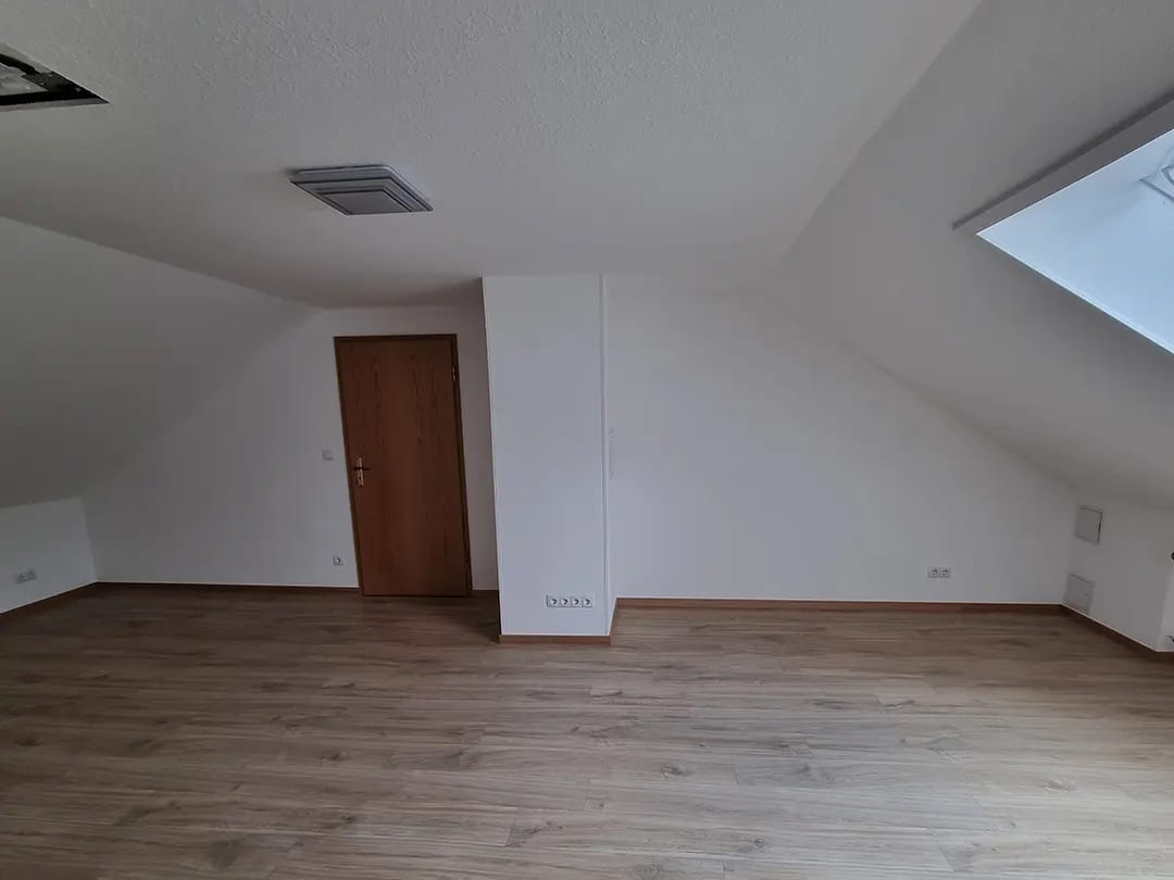 Derselbe Raum nach dem Ausbau mit hellen Dachschrägen, Dachfenster und neuem Bodenbelag in Holzoptik