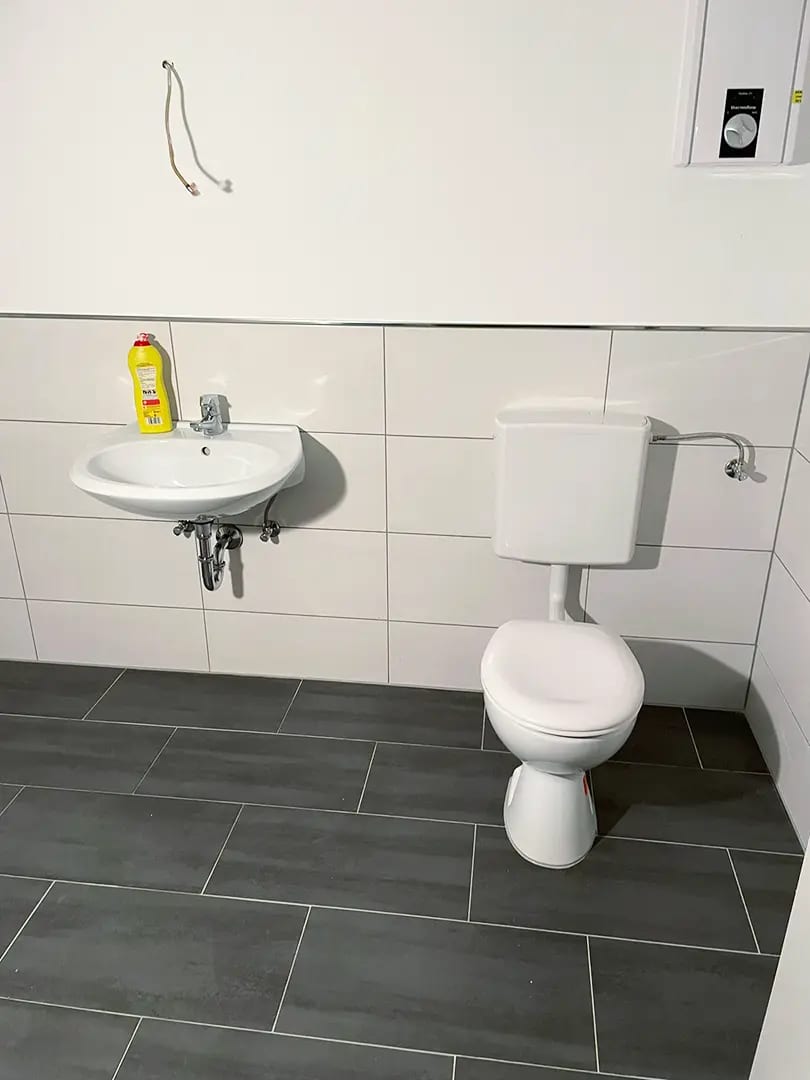 WC mit Spülkasten und Waschbecken im neu verfliesten Bad