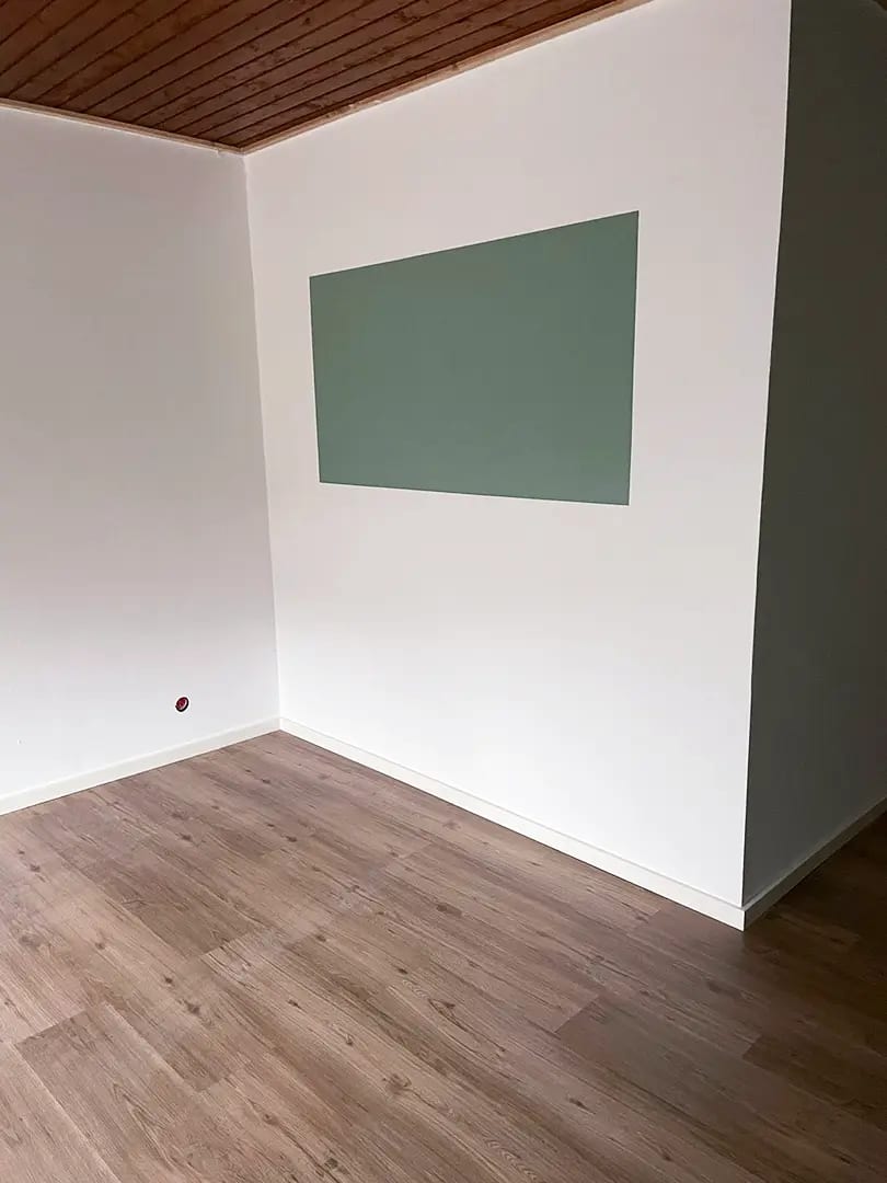 Wohnraum mit Streichputz, grün abgesetzter Wandfläche und neuem Vinylboden