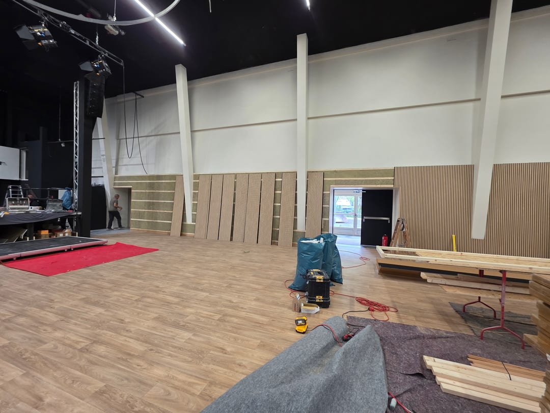 Montage der Akustikpaneele an der Hallenwand, ein Teil der Paneele lehnt noch an der Dämmung